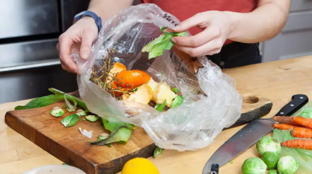 Produce scraps being put into a compost bag on a kitchen counter